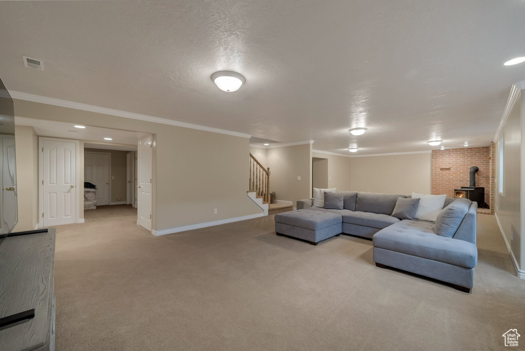 Living area with light colored carpet, stairs, crown molding, baseboards, and a wood stove