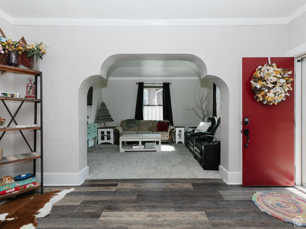 Foyer featuring arched walkways, ornamental molding, dark wood-type flooring, plenty of natural light, and baseboards
