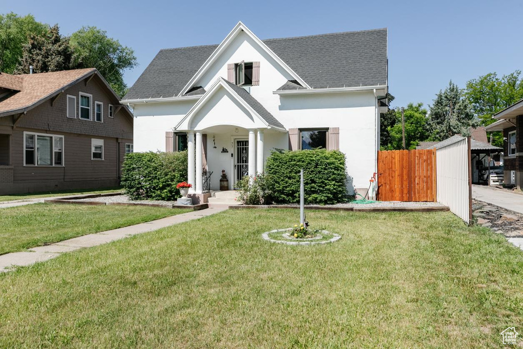 View of front of home with stucco siding, roof with shingles, and a front lawn