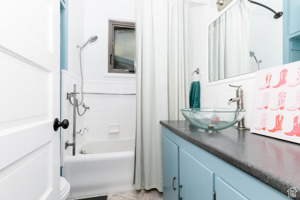 Bathroom with shower / bath combination with curtain, vanity, toilet, and decorative backsplash