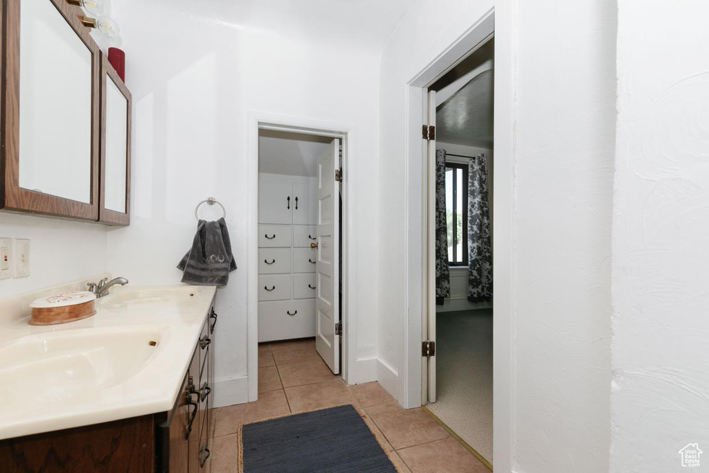 Bathroom featuring double vanity, tile patterned floors, and baseboards