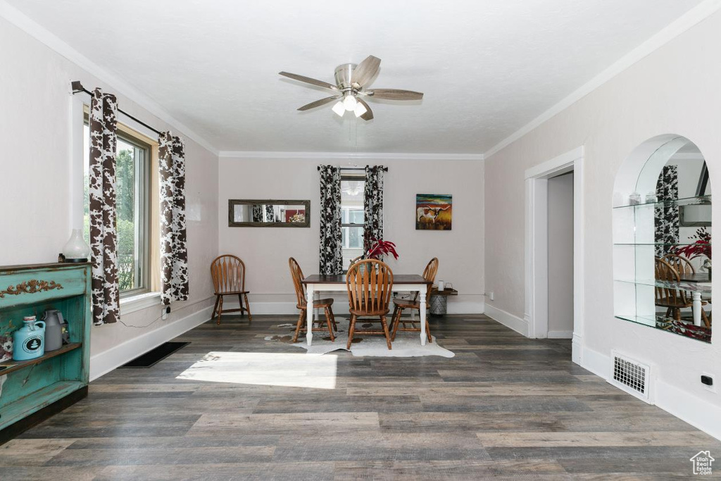 Dining room featuring ceiling fan, crown molding, baseboards, and wood finished floors