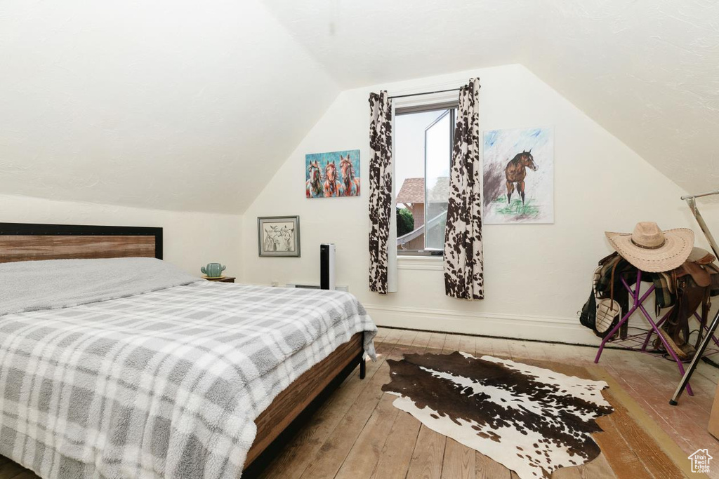 Bedroom featuring hardwood / wood-style floors, lofted ceiling, and baseboards
