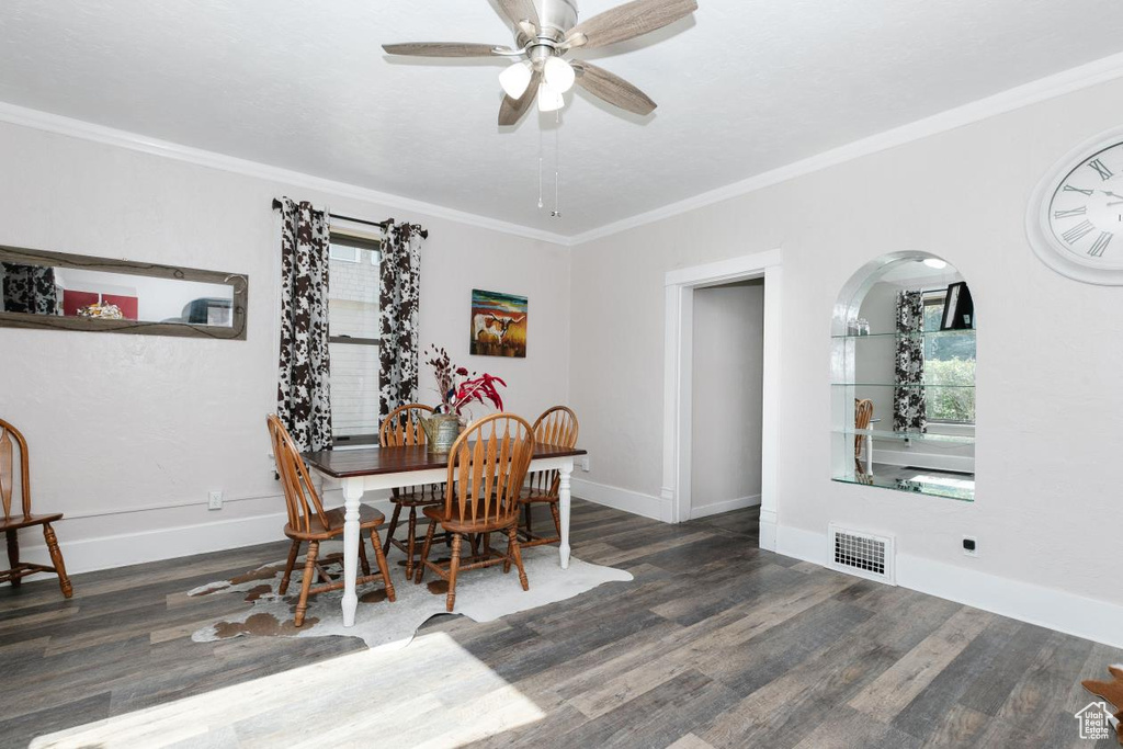 Dining area with a ceiling fan, wood finished floors, ornamental molding, and baseboards