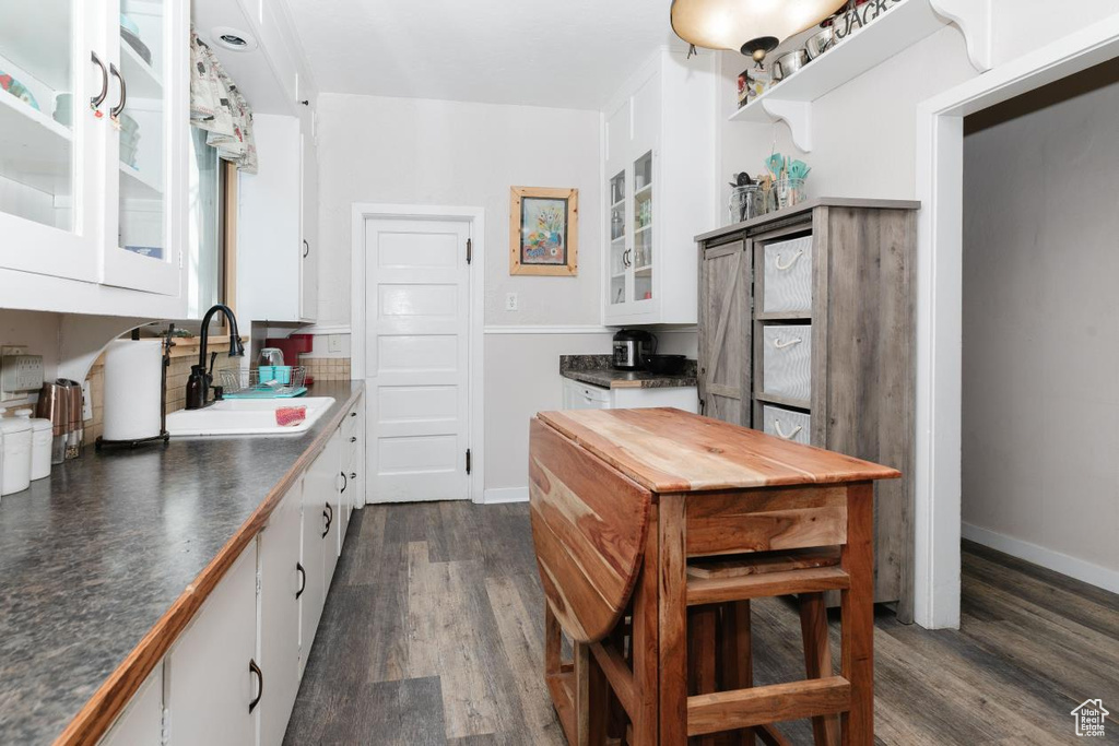 Kitchen featuring a sink, white cabinetry, and dark wood-style flooring