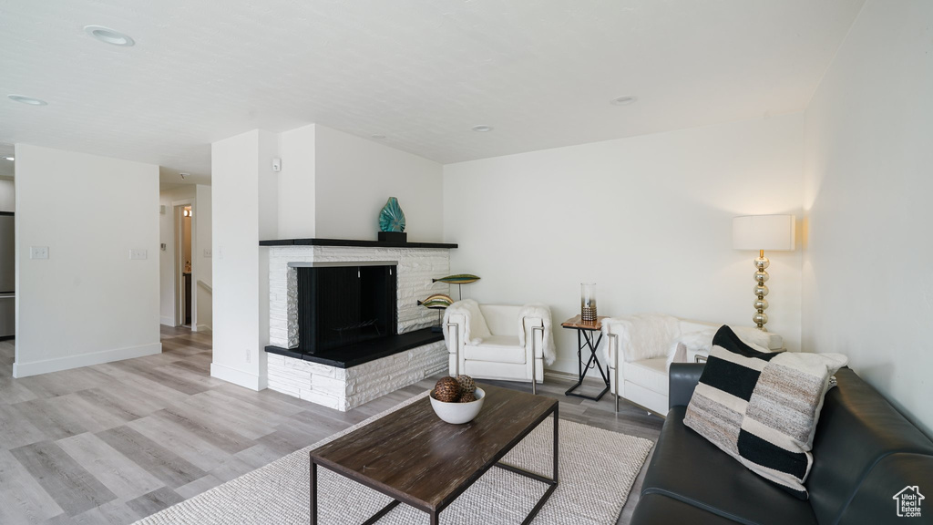 Living room featuring a stone fireplace, wood finished floors, baseboards, and recessed lighting