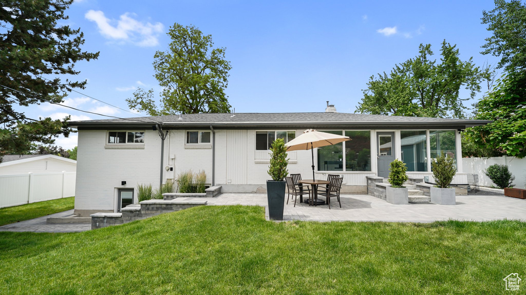 Back of property with a patio, a chimney, brick siding, and a sunroom