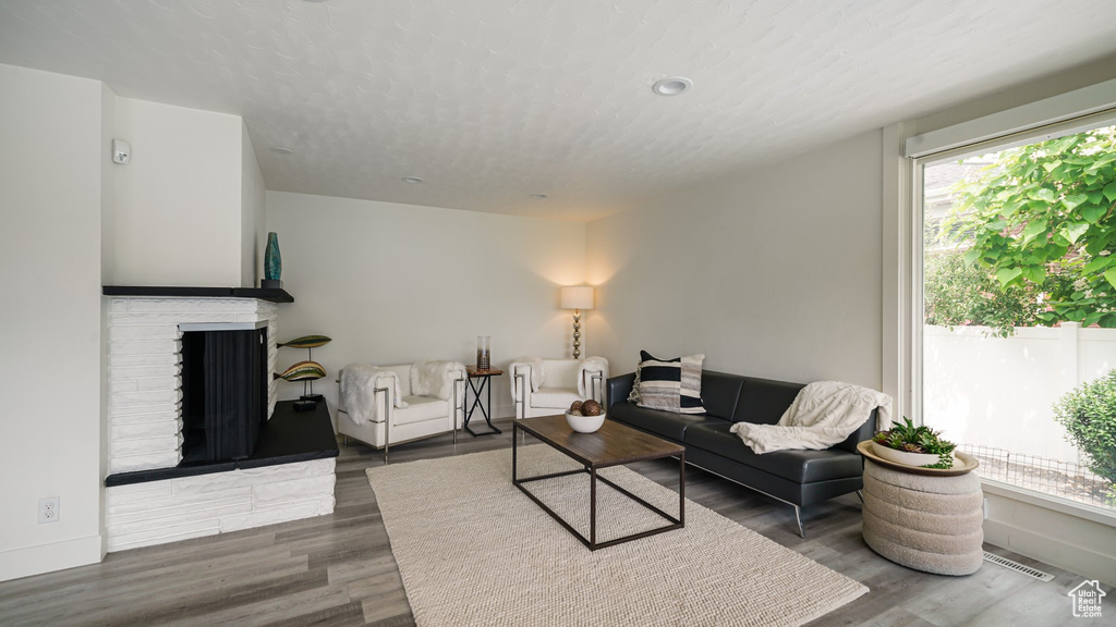 Living room featuring plenty of natural light, a brick fireplace, and wood finished floors