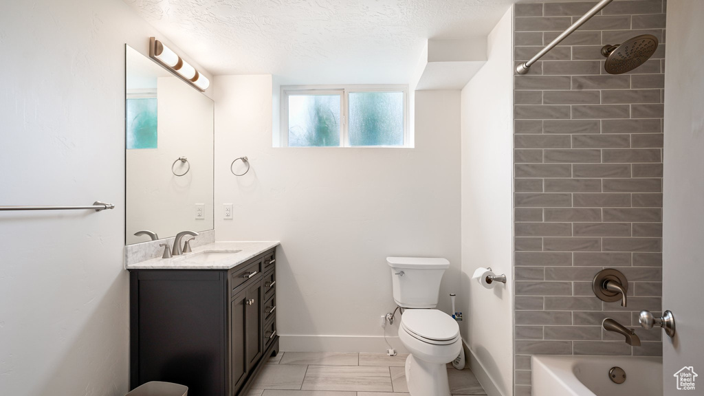 Full bath with toilet, vanity, marble look tile flooring, tub / shower combination, and baseboards