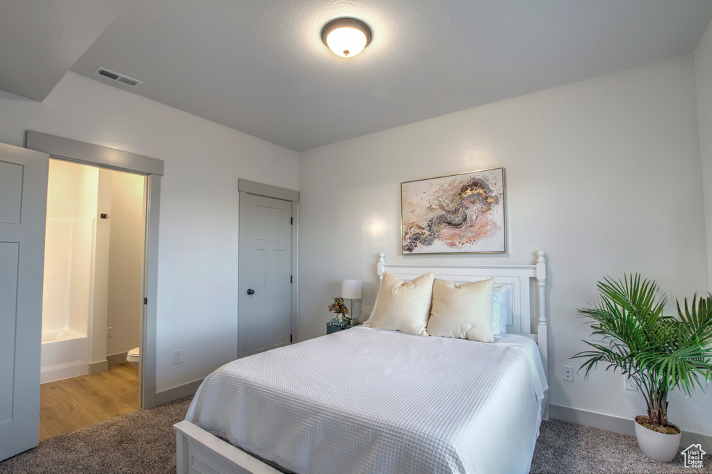 Bedroom featuring baseboards, light colored carpet, and ensuite bath