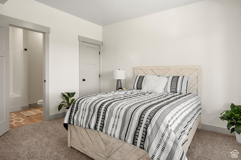 Carpeted bedroom with baseboards and connected bathroom