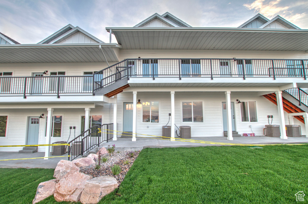 View of front of property with a front yard, cooling unit, and board and batten siding
