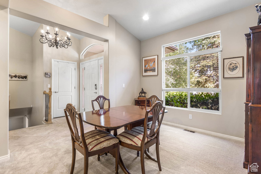 Dining area with lofted ceiling, light carpet, baseboards, and a chandelier