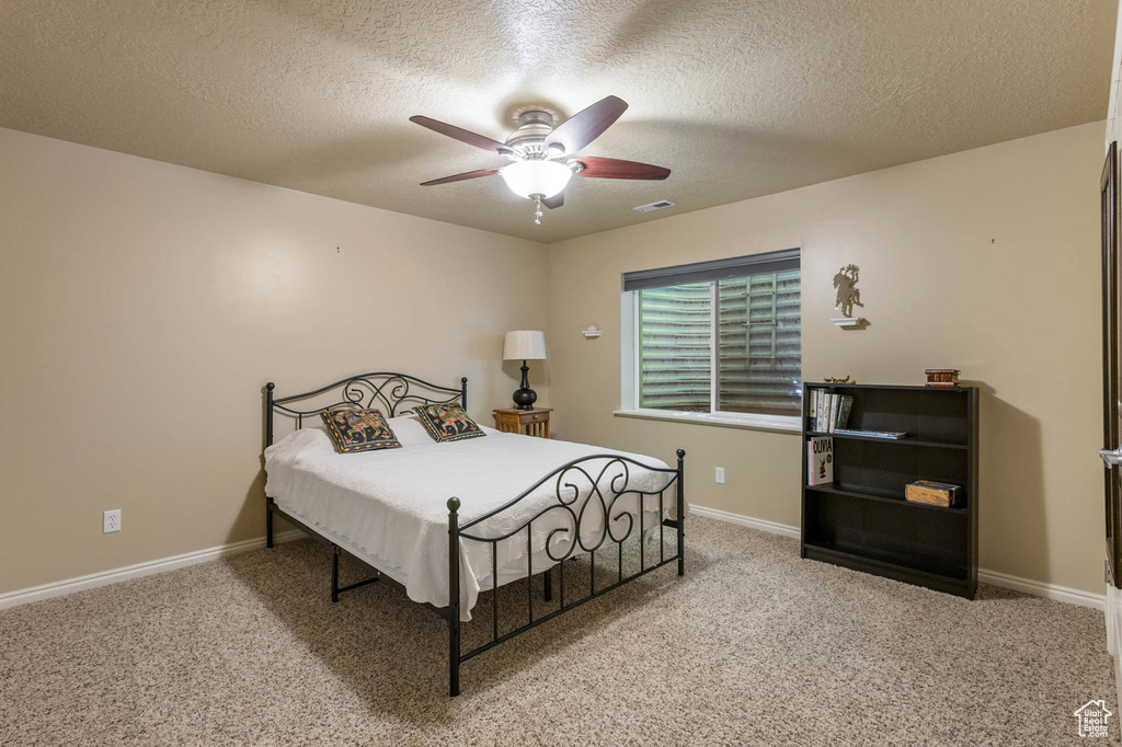 Bedroom featuring a textured ceiling, carpet, baseboards, and a ceiling fan