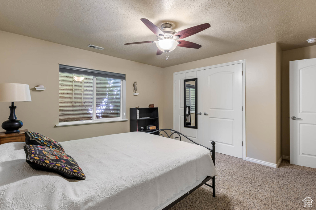 Carpeted bedroom with a textured ceiling, baseboards, and ceiling fan