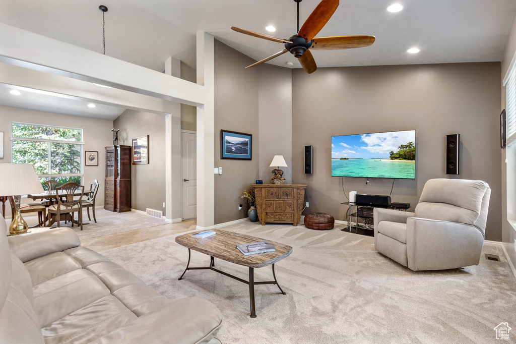 Carpeted living area with recessed lighting, ceiling fan, baseboards, and a high ceiling