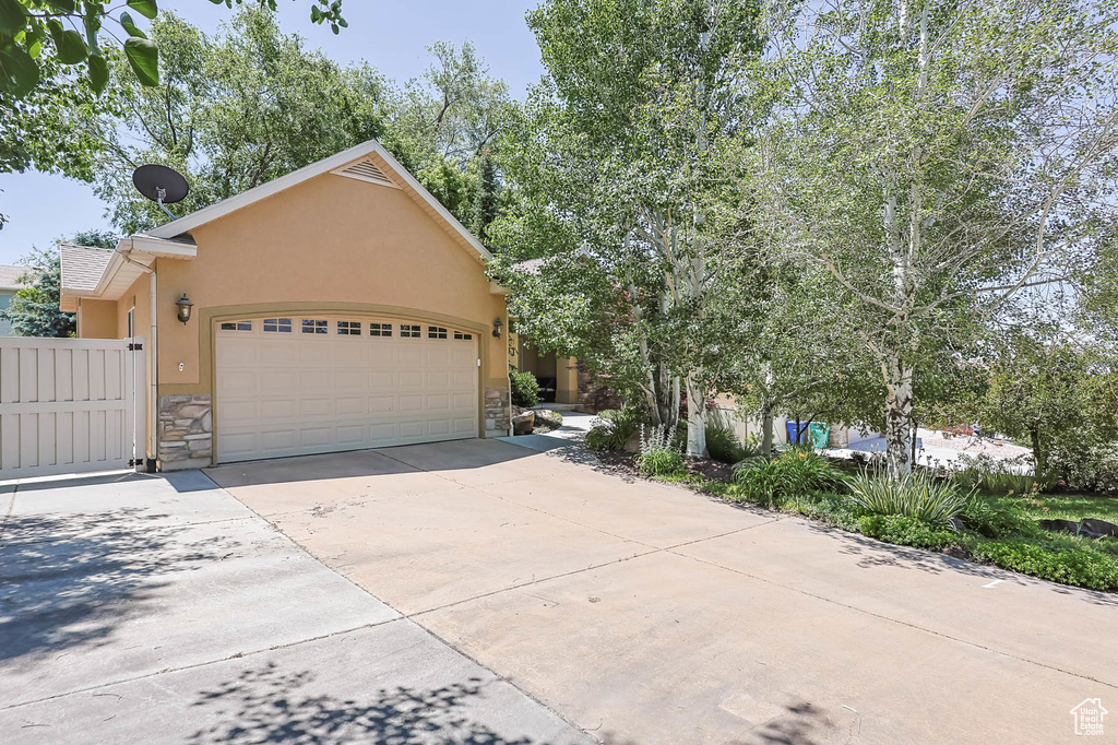 View of front of home with stone siding, stucco siding, an attached garage, and driveway