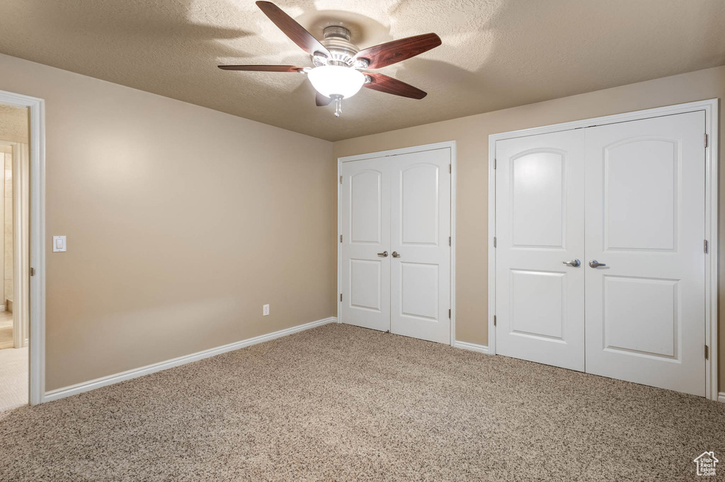 Unfurnished bedroom with carpet flooring, baseboards, a ceiling fan, a textured ceiling, and a closet