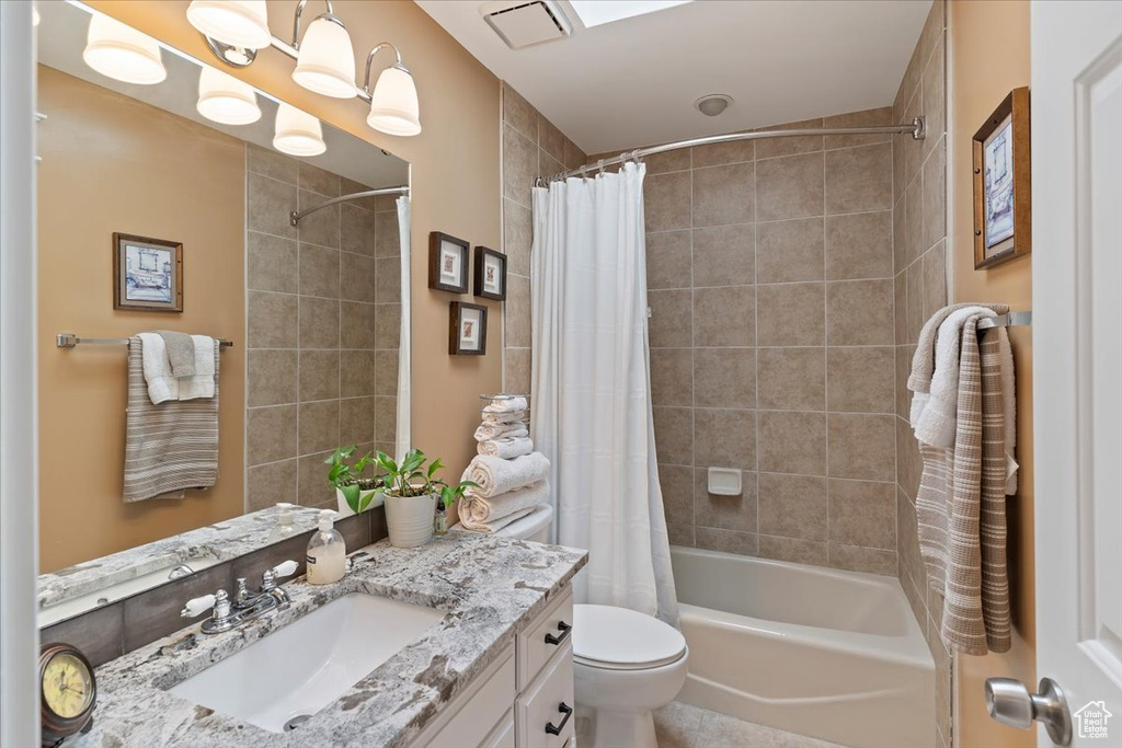 Bathroom featuring vanity, shower / bath combo, and toilet