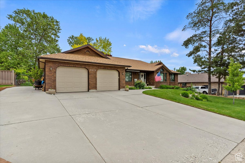 Single story home featuring a garage, concrete driveway, brick siding, and a shingled roof