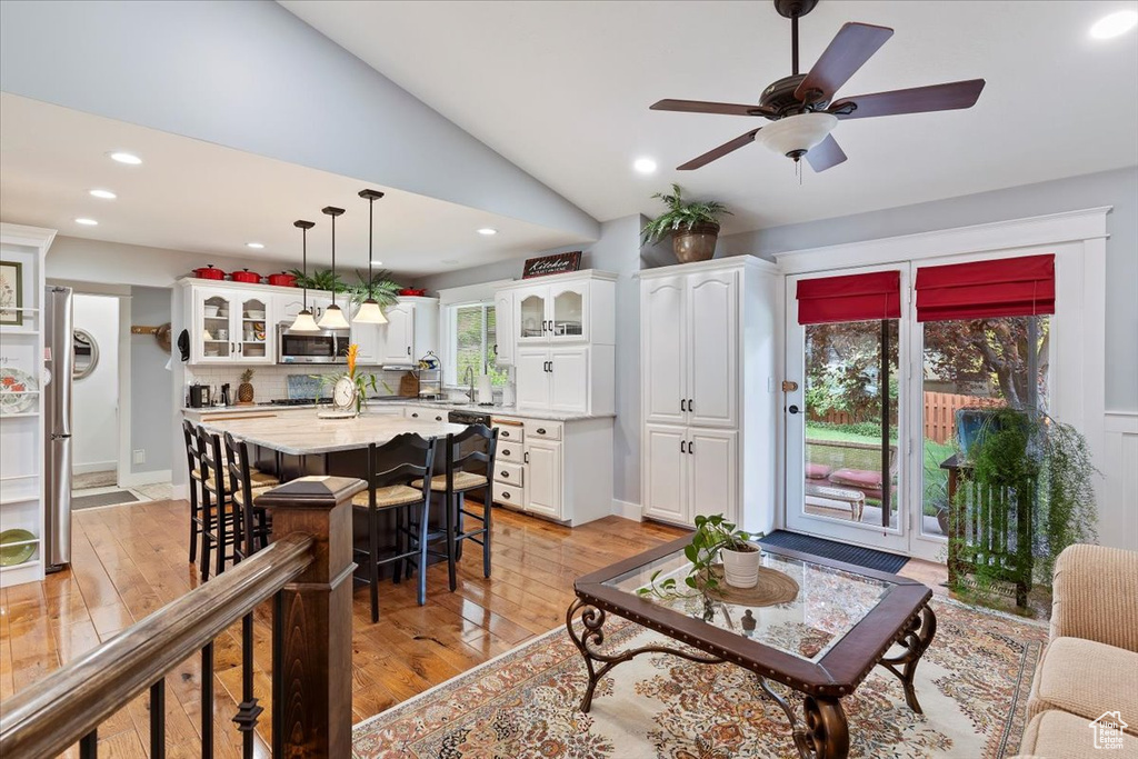 Living area with light wood-style floors, recessed lighting, vaulted ceiling, and ceiling fan
