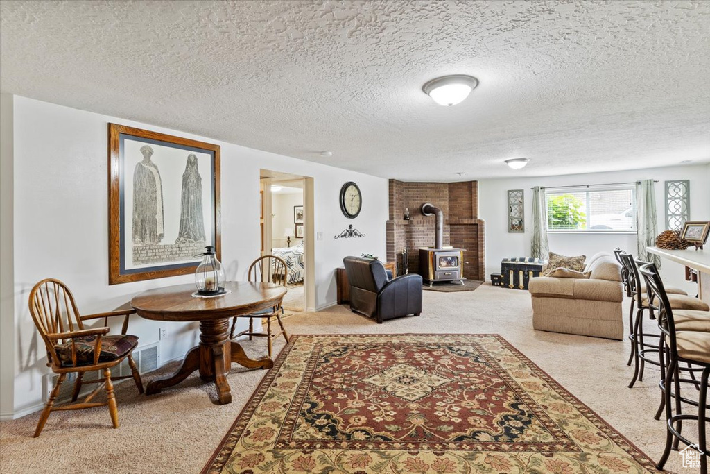 Living area featuring a wood stove, light colored carpet, and a textured ceiling