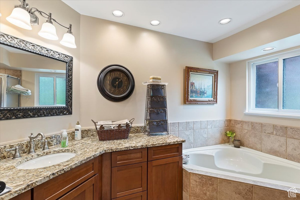 Full bathroom with a garden tub, vanity, a shower with shower door, and recessed lighting
