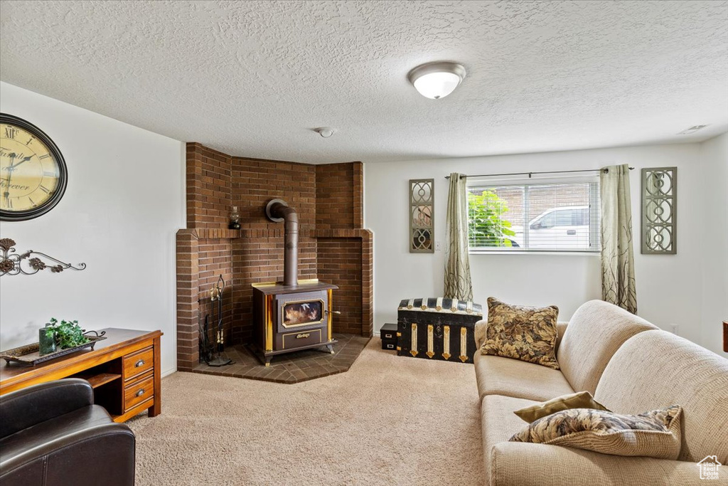 Carpeted living room featuring a wood stove and a textured ceiling
