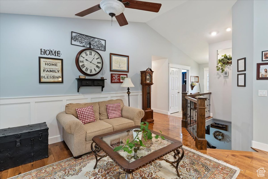 Living area with vaulted ceiling, ceiling fan, hardwood / wood-style flooring, and wainscoting