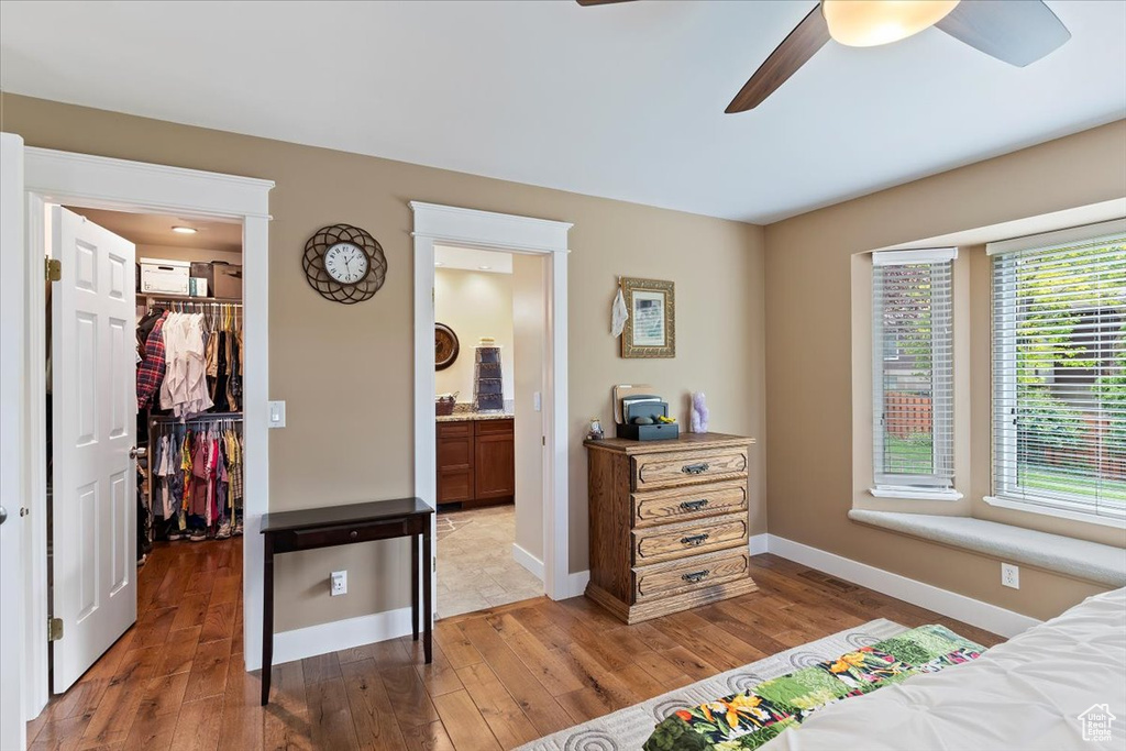 Bedroom featuring a spacious closet, light wood-type flooring, baseboards, ensuite bath, and a closet
