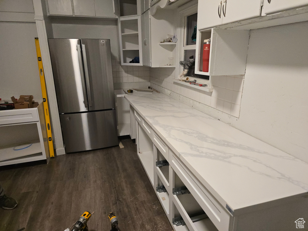 Kitchen with freestanding refrigerator, tasteful backsplash, dark wood-type flooring, and light stone countertops