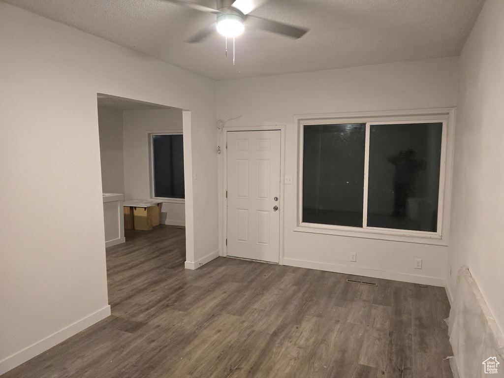 Unfurnished room with dark wood-style floors, a ceiling fan, baseboards, and a textured ceiling