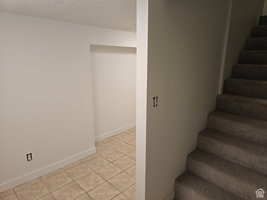 Staircase with tile patterned floors and baseboards