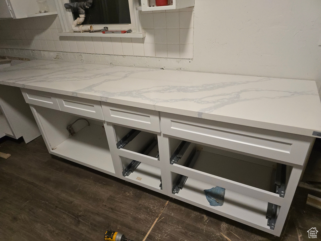 Detailed view of dark wood-type flooring, light stone counters, and backsplash