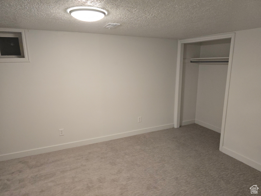 Unfurnished bedroom with a textured ceiling, carpet flooring, a closet, and baseboards