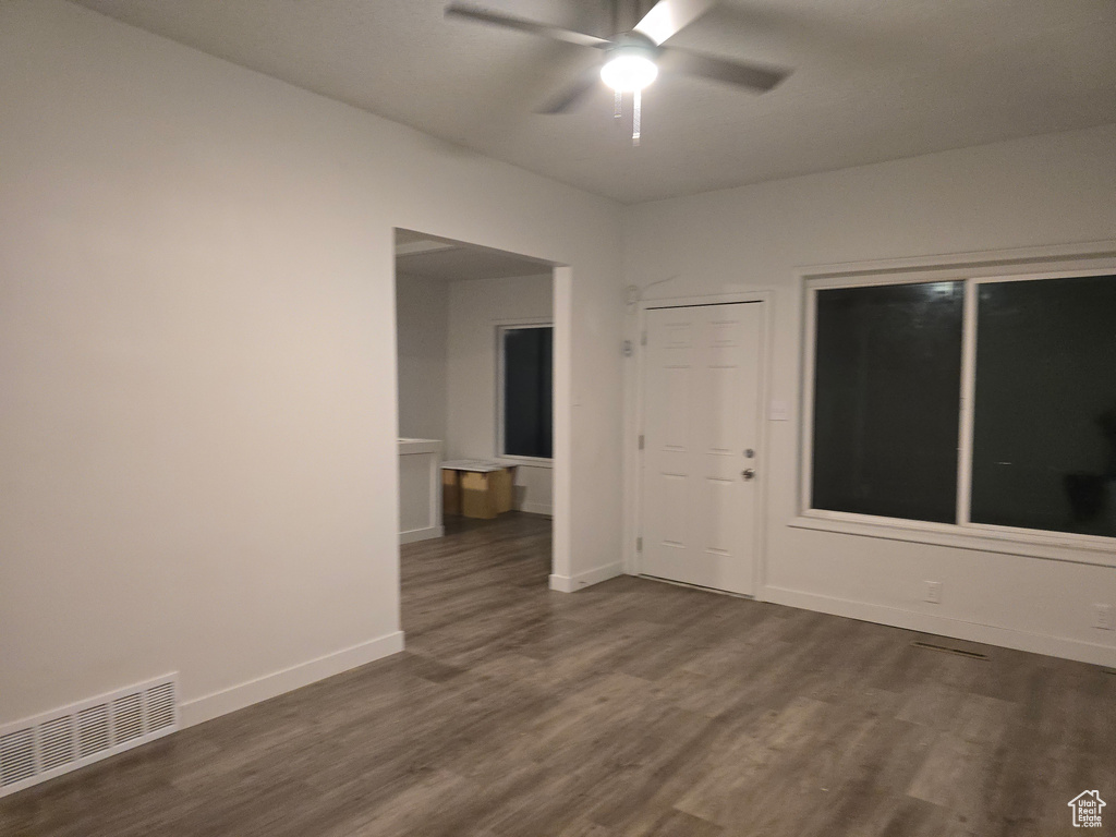Unfurnished room featuring a ceiling fan, dark wood finished floors, and baseboards