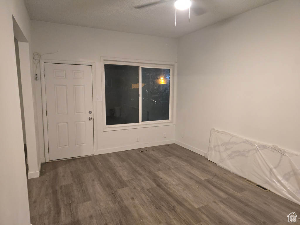 Empty room with dark wood finished floors, a ceiling fan, and baseboards