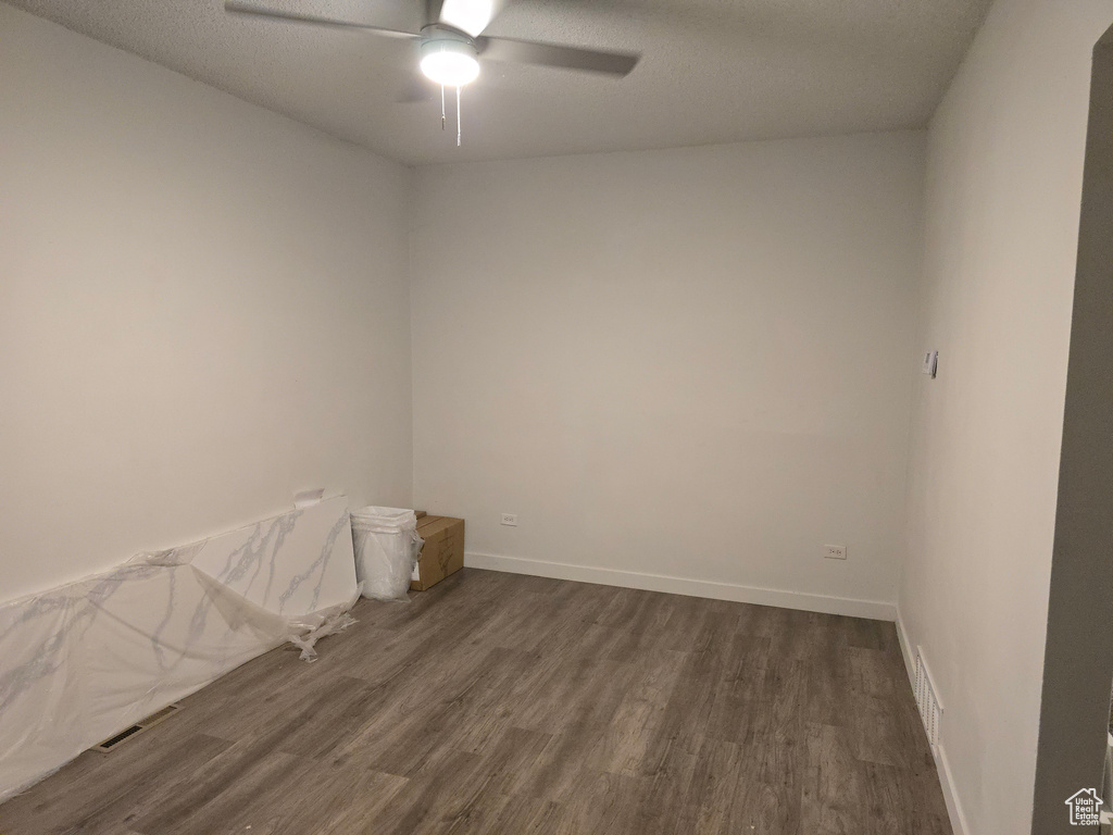 Empty room with dark wood finished floors, ceiling fan, and baseboards