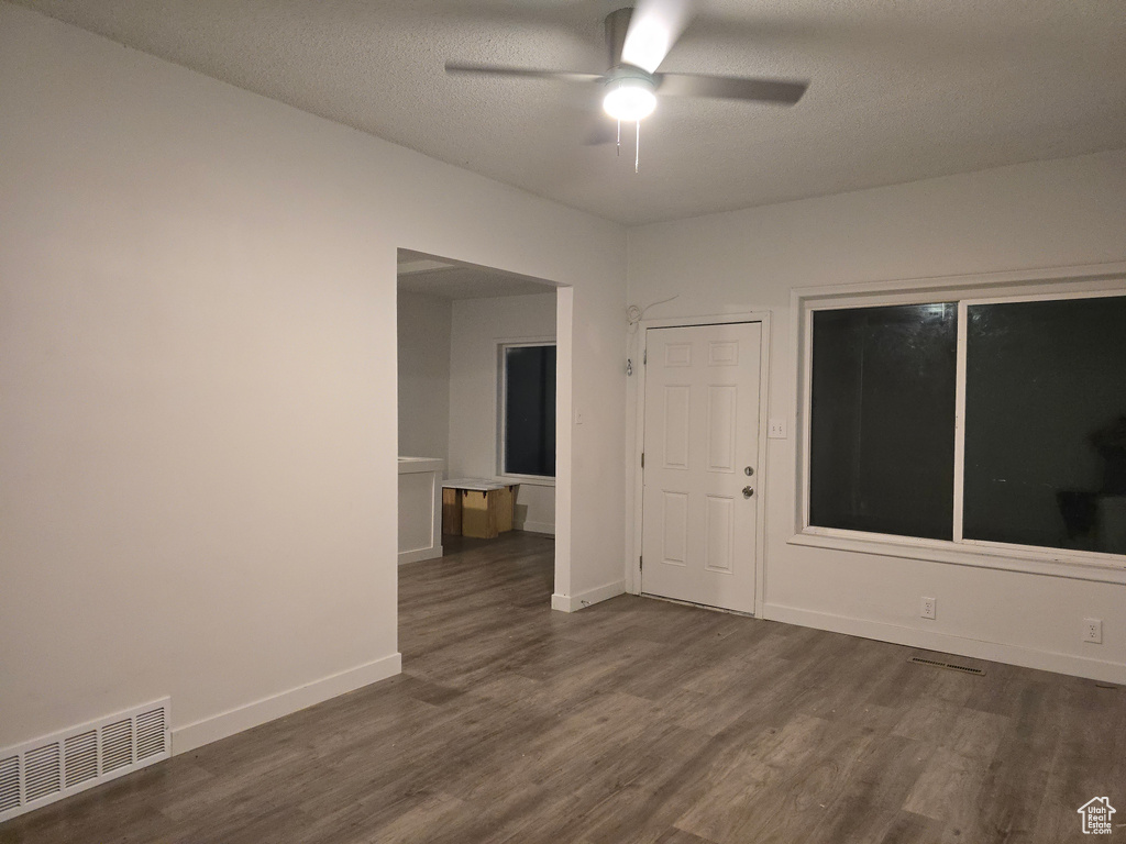 Unfurnished room with dark wood-type flooring, ceiling fan, baseboards, and a textured ceiling