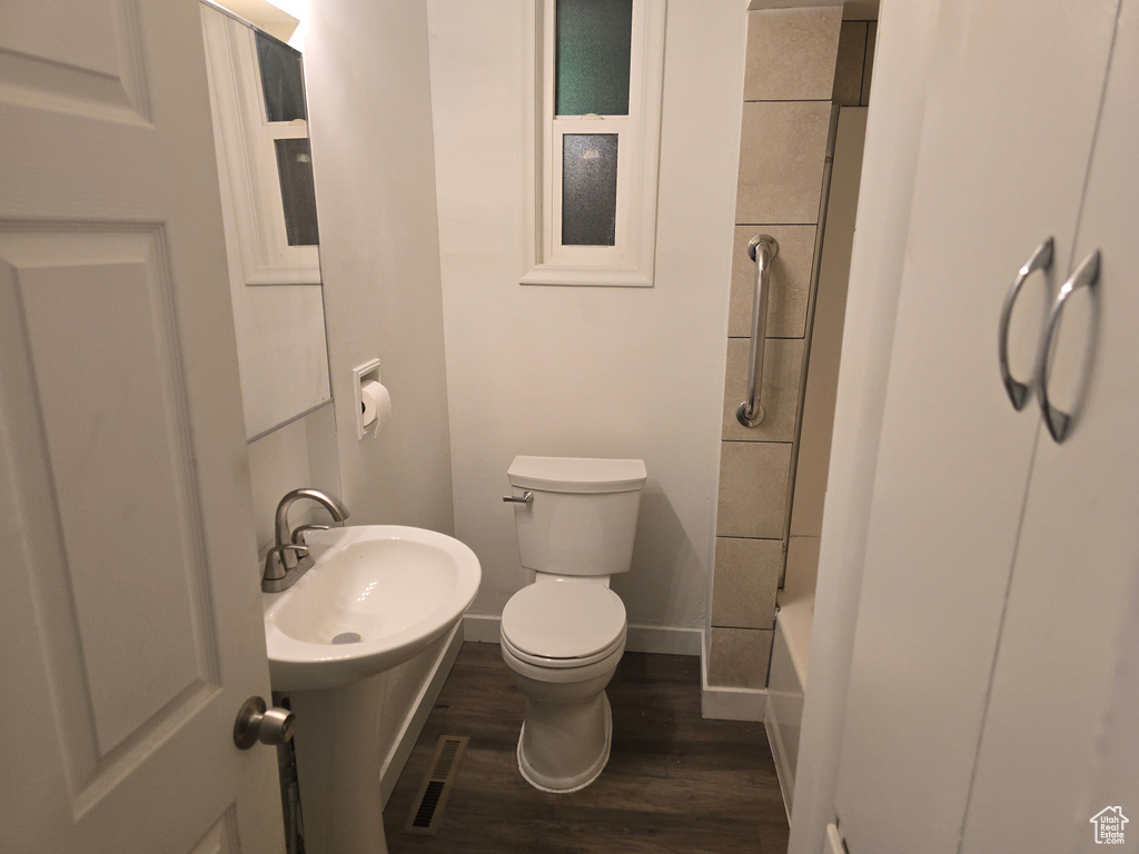 Full bath featuring wood finished floors, toilet, baseboards, and tub / shower combination