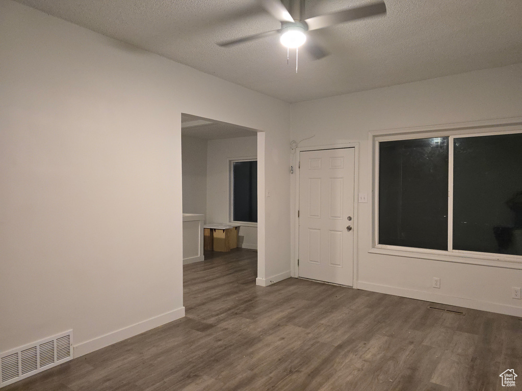 Unfurnished room featuring dark wood-style flooring, ceiling fan, a textured ceiling, and baseboards