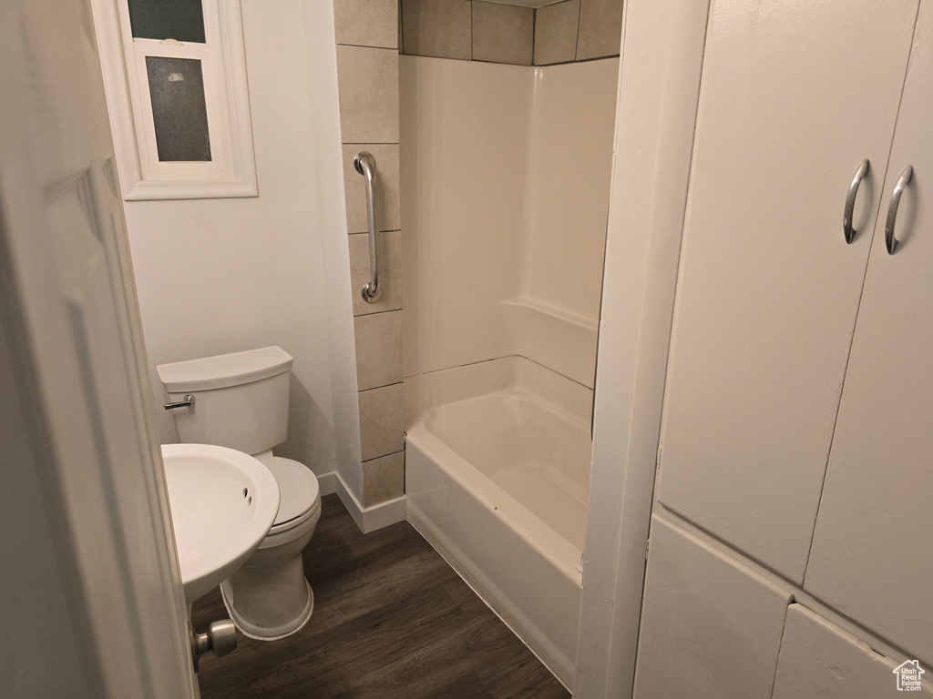 Full bath with toilet, wood finished floors, shower / washtub combination, and baseboards