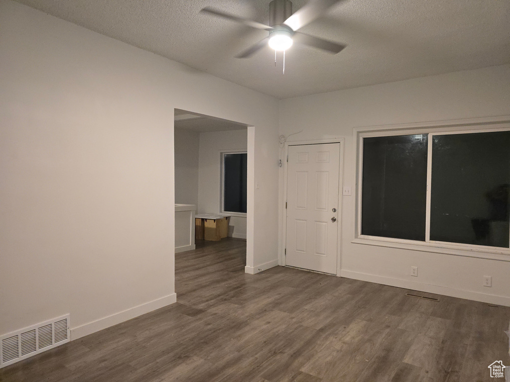 Spare room with dark wood finished floors, a ceiling fan, a textured ceiling, and baseboards