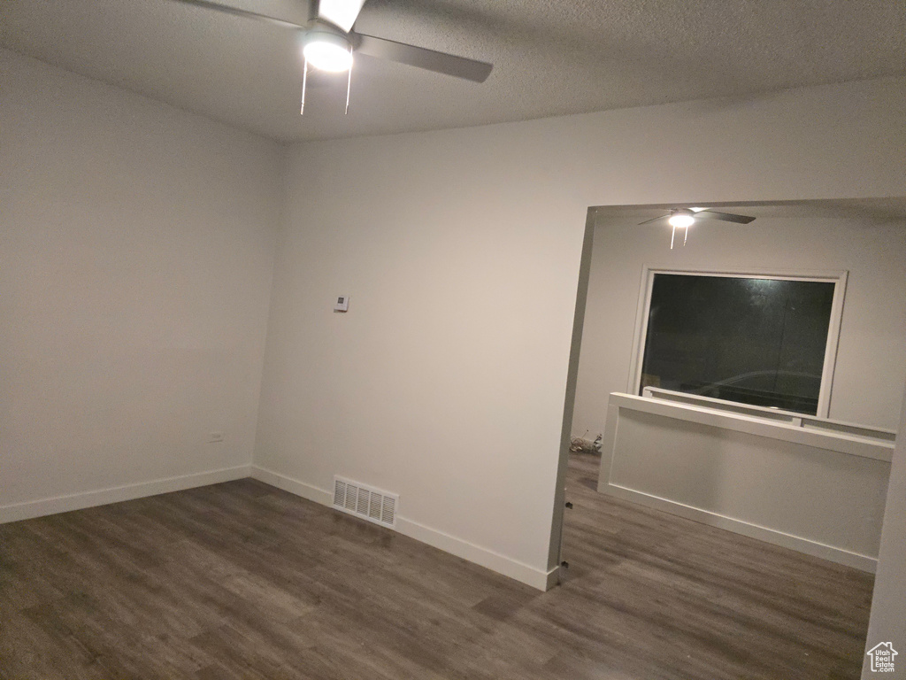 Spare room with a ceiling fan, wood finished floors, baseboards, and a textured ceiling