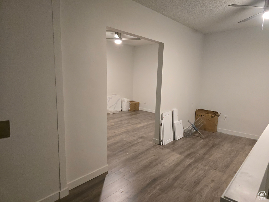 Empty room with a ceiling fan, dark wood finished floors, a textured ceiling, and baseboards