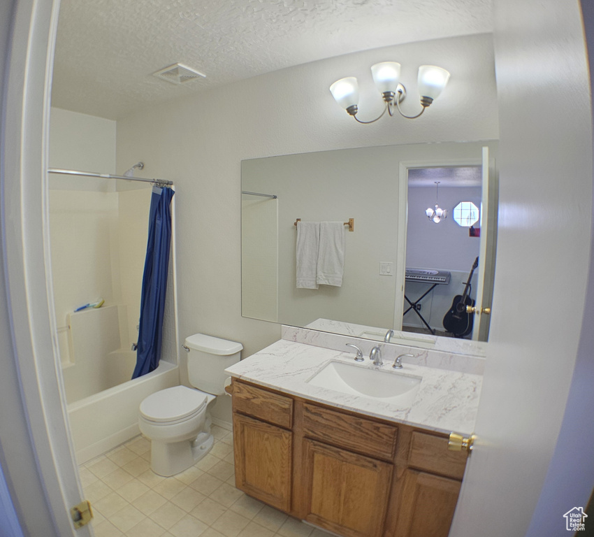Full bathroom with toilet, vanity, shower / tub combo with curtain, tile patterned flooring, and a textured ceiling