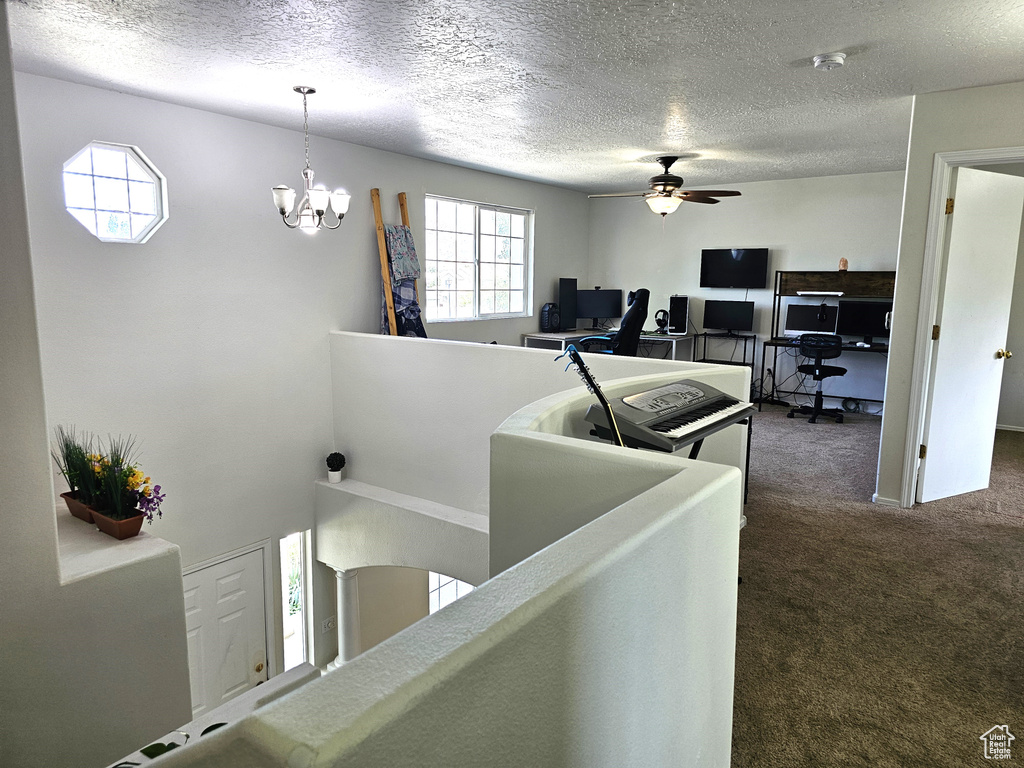 Staircase featuring carpet, a ceiling fan, a textured ceiling, and a chandelier