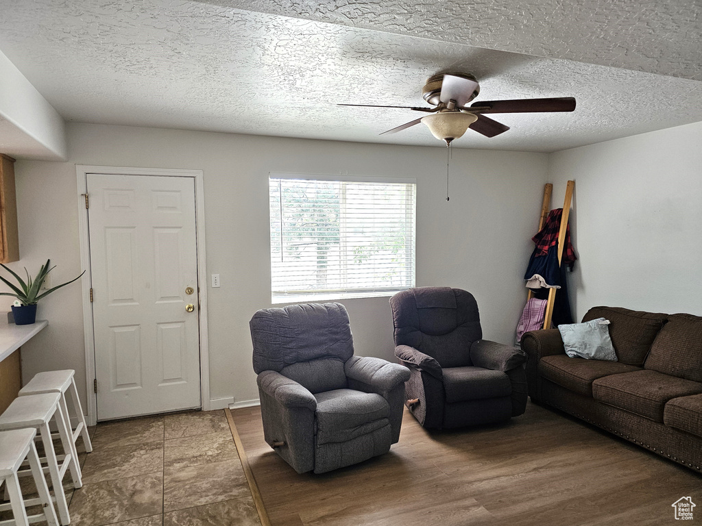Living room with a ceiling fan, wood finished floors, and a textured ceiling