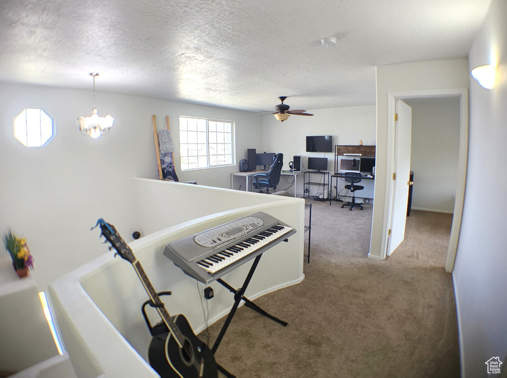 Hallway with carpet, a desk, a textured ceiling, and a chandelier