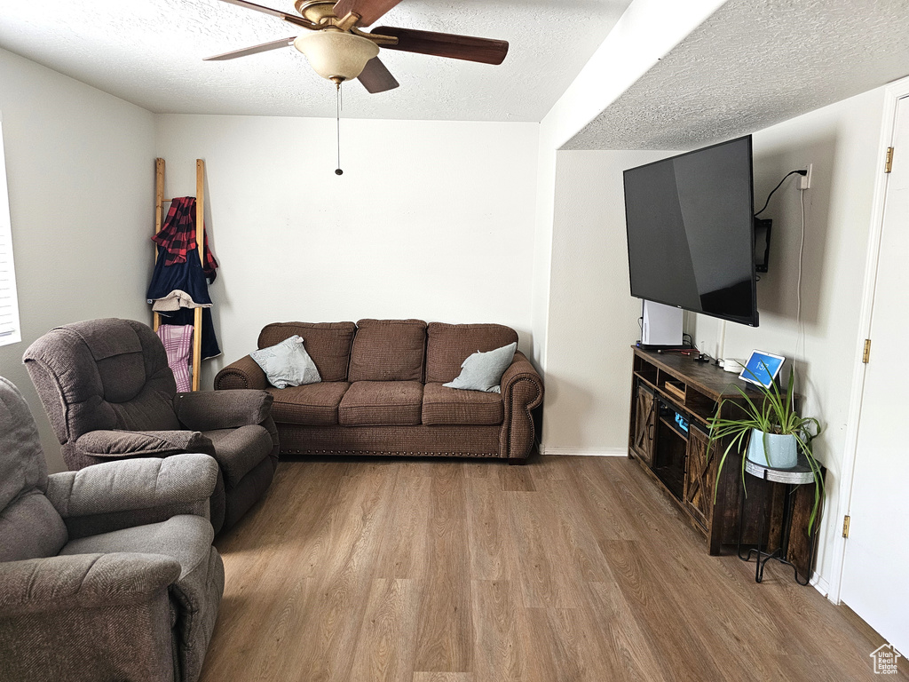Living area with wood finished floors, a ceiling fan, a textured ceiling, and baseboards